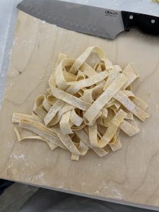 Pile of fettuccine noodles on cutting board.