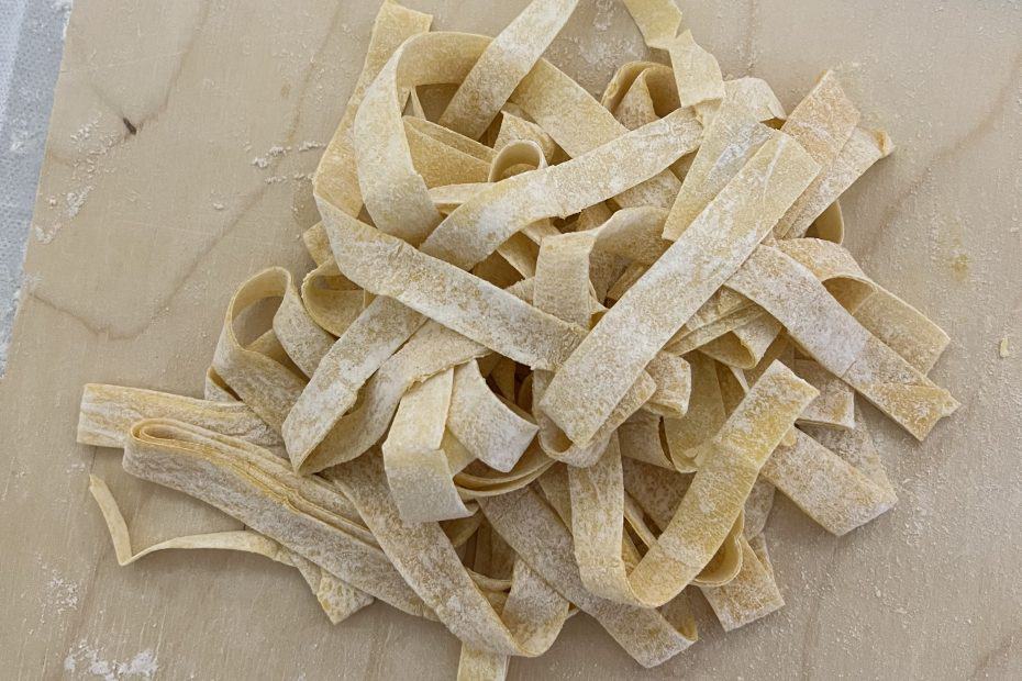 Pile of fettuccine noodles on cutting board.