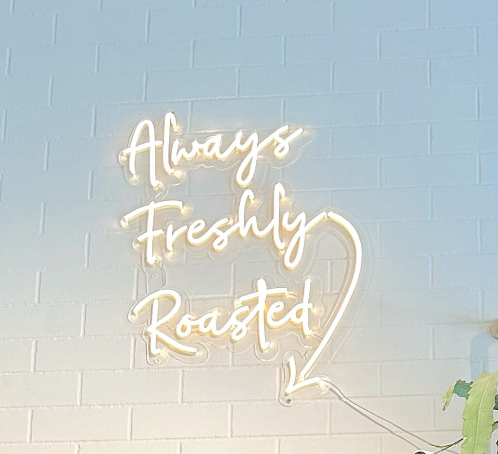 Light up sign that says always freshly roasted.