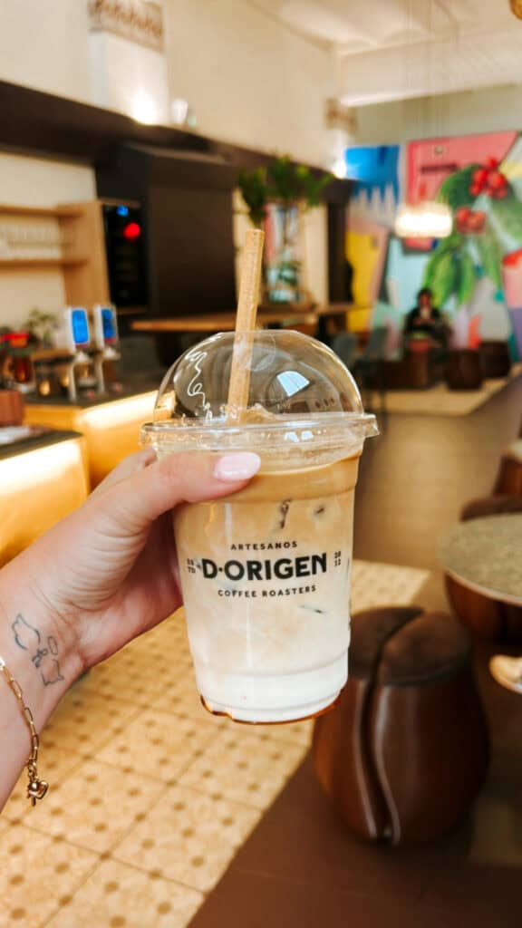 Hand holding an iced coffee with an edible straw.