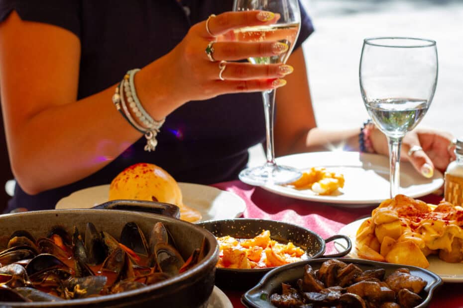 Girl holding wine glass at a table of tapas.