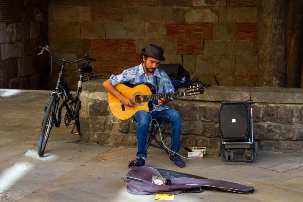 Man playing guitar on the street with an amp.