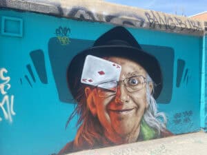 A detailed street painting of an old man with a card in his glasses.