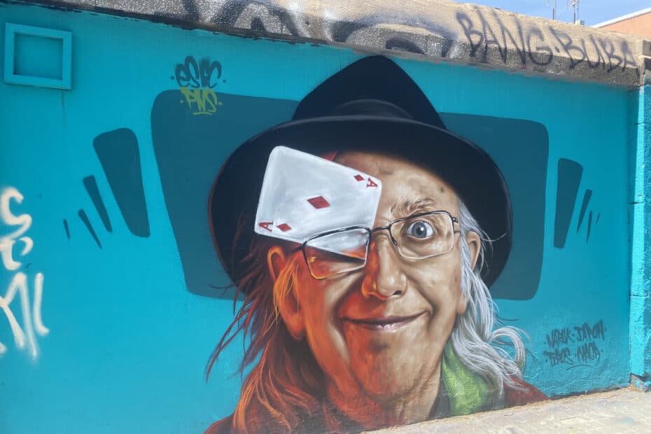 A detailed street painting of an old man with a card in his glasses.