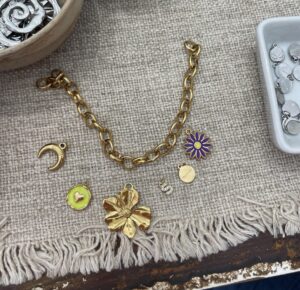 A gold charm bracelet with colorful and fun charms ready to be made.