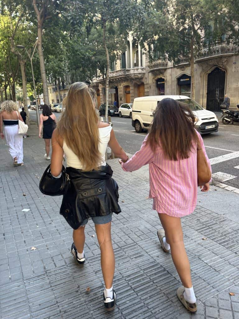 two girls walking down the street, arm in arm.