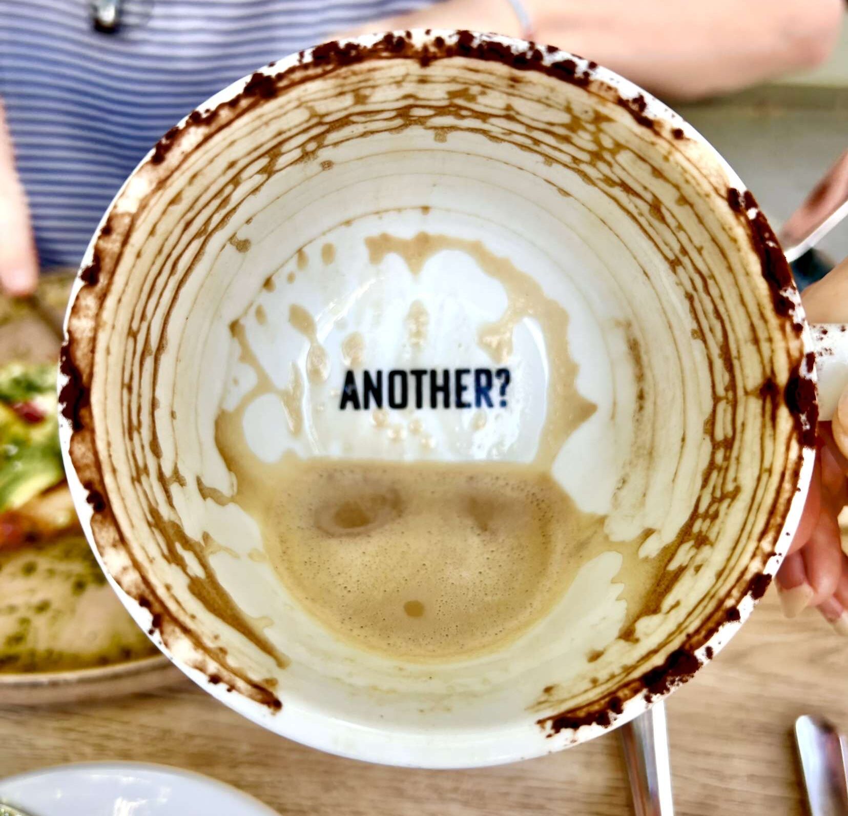 The empty bottom of a coffee cup, revealing the word “Another?” 