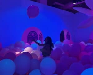 girl throwing bubble in giant ball pit at bubble planet.