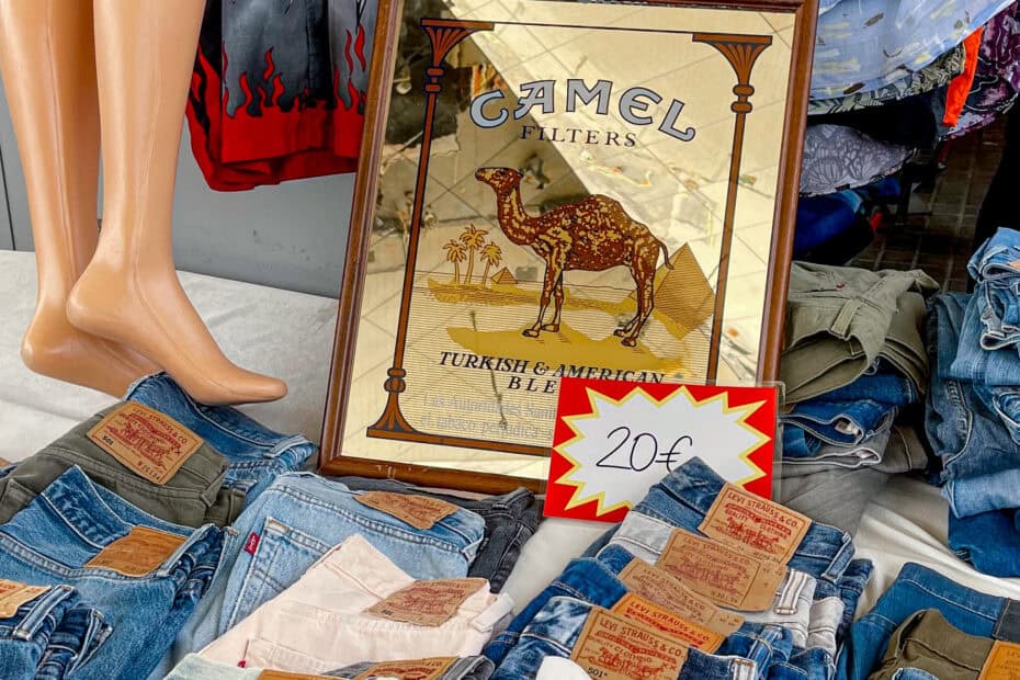 second-hand Levi jeans, mannequin legs, and a Camel Cigarette sign sit at a table at the market.