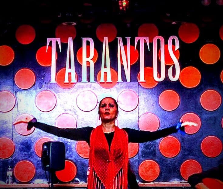 A flamenco dancer posing underneath the name of the club, "Tarantos."