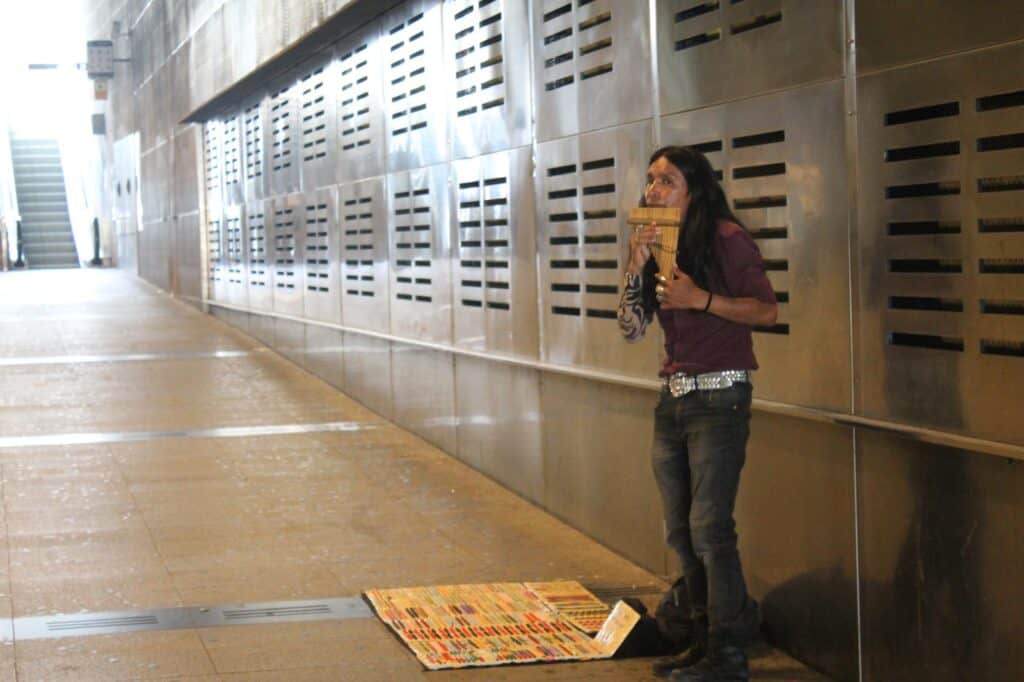 Woman playing a pan flute standing in the metro.