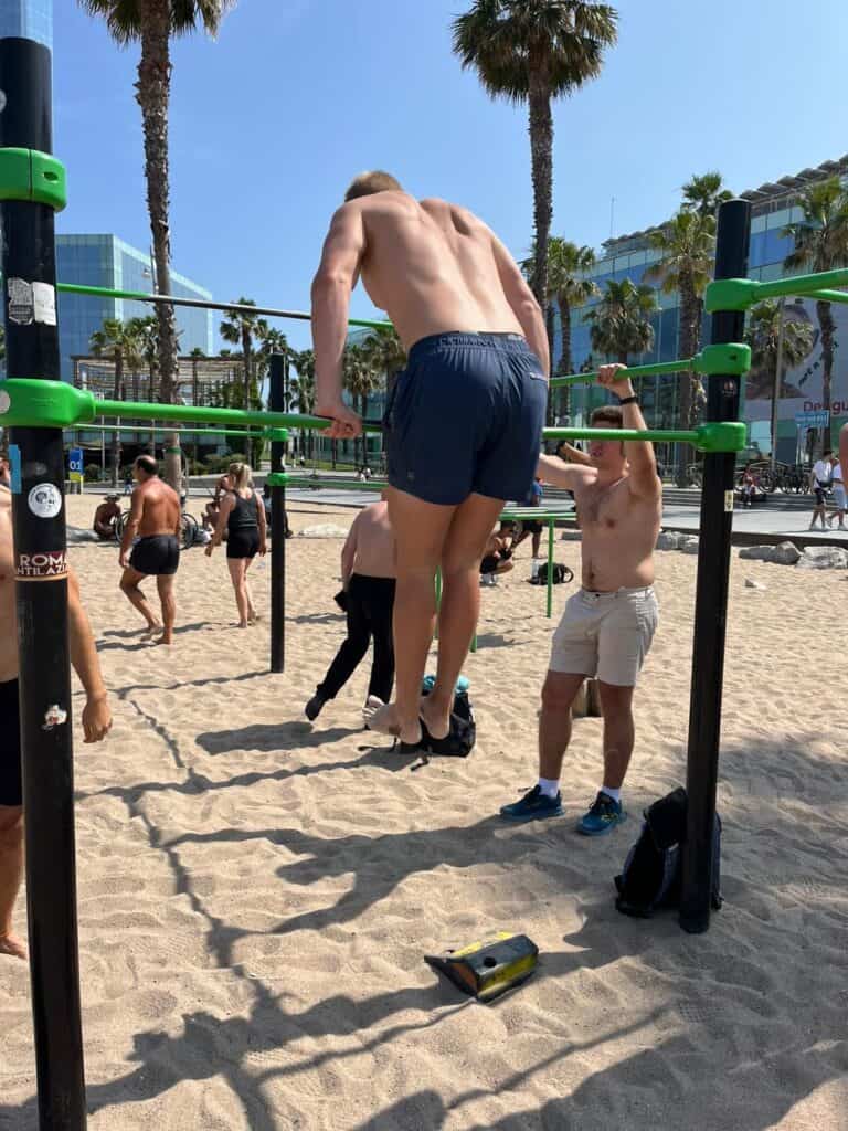 Jacob is doing a muscle-up at the outdoor gym.