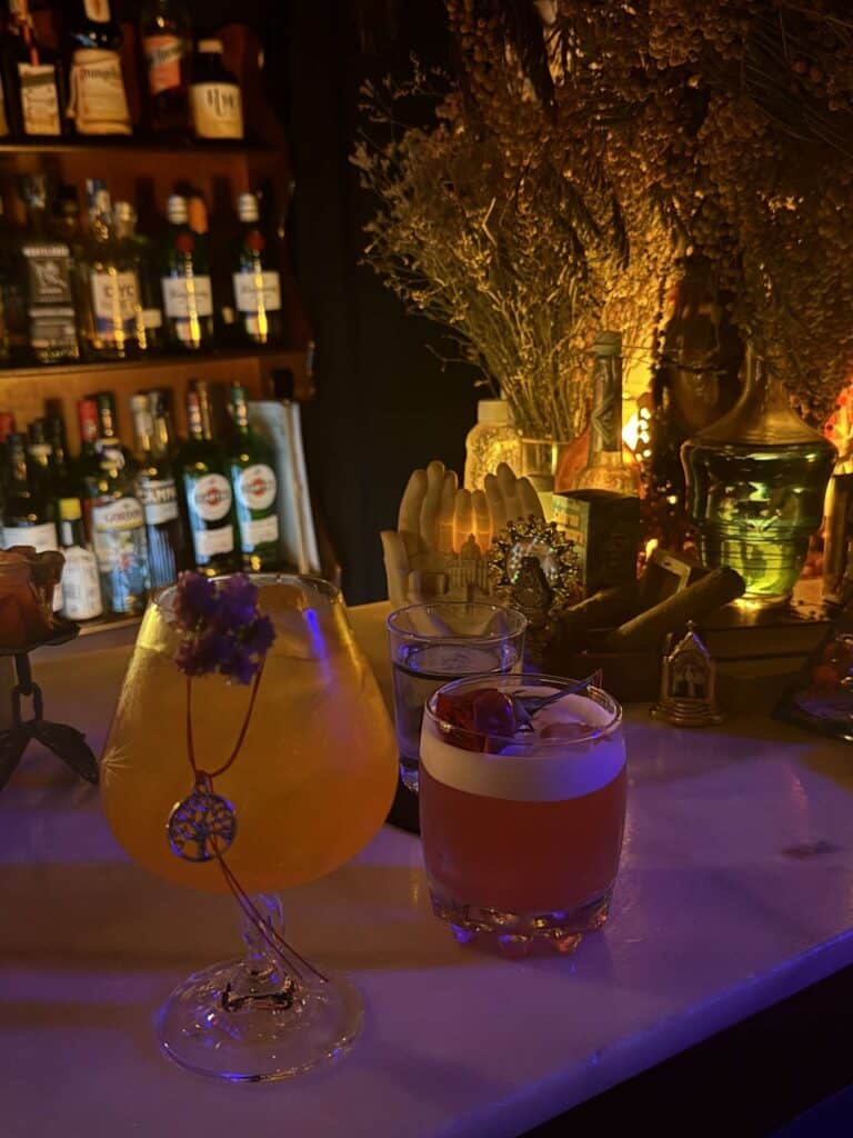 Image of two cocktails with charms attached to them on a bar counter.