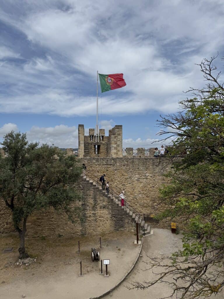 [Image ID]: The flag of Portugal is flown from a guard tower in the historic Castelo de São Jorge in Lisbon, Portugal.