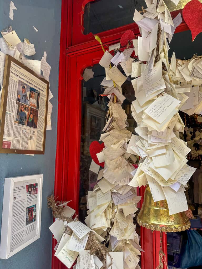 The storefront covered in handwritten notes, with heart decorations and a golden bell to send the wishes out to the world.