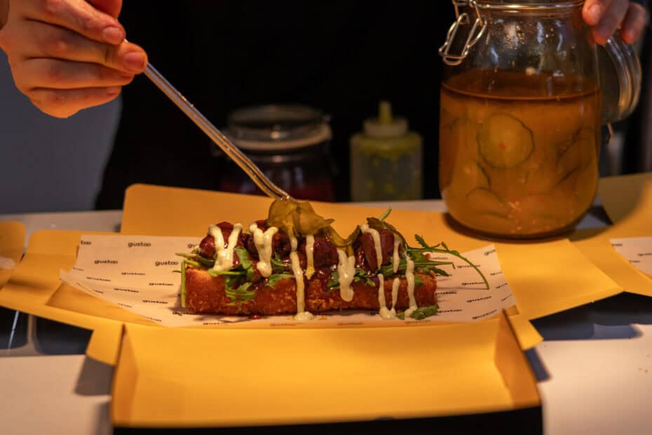 the chef places a pickle over the rib brioche dish