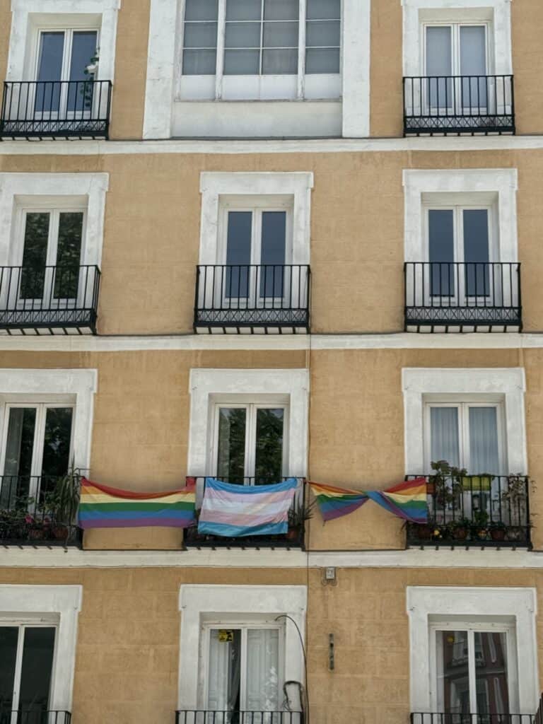 Two traditional and one transgender pride flags hanging from residential balconies
