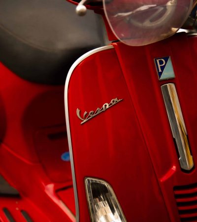 A Red Vespa moped is parked on the street in Trastevere, Rome, Italy. These vehicles are often a favorite for locals and are iconic Italian trademarks. Photo by Sarah Sharpe.